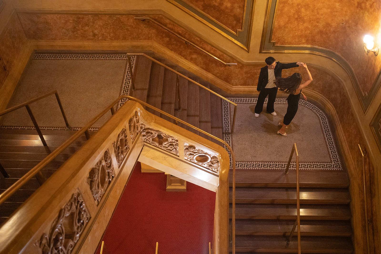 Bryan and Sheryl on the sweeping staircase in warm golden light