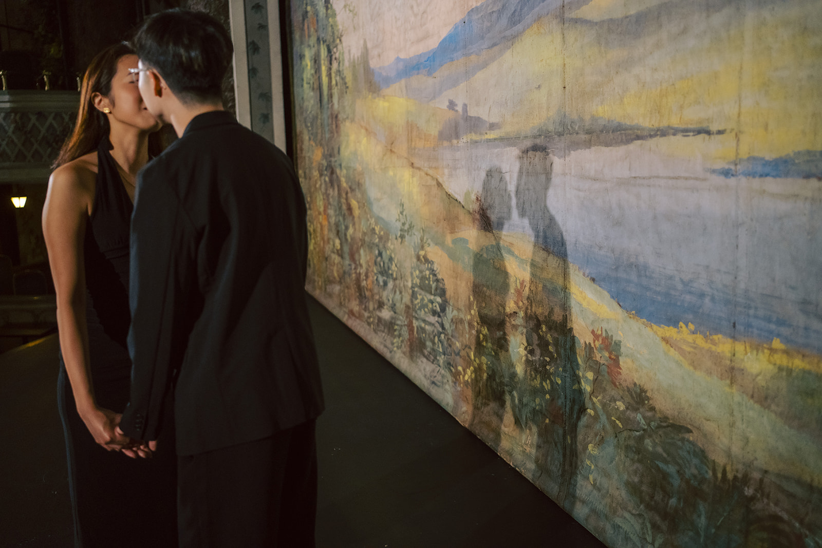 Bryan and Sheryl holding hands beside the painted landscape